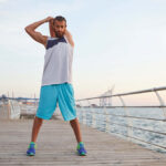 young-sporty-bearded-guy-doing-warm-up-after-morning-run-seaside-looks-away